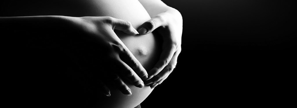 33410670 - close-up of a pregnant woman's tummy. over black background